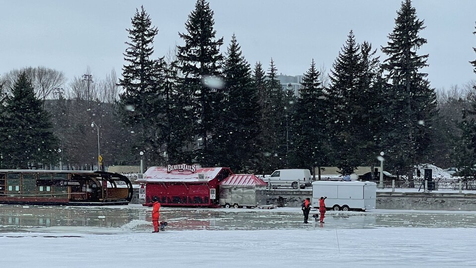 Des personnes travaillent sur un canal glacé, en extérieur.