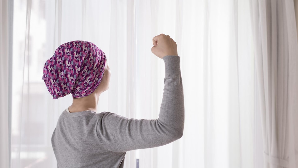 Une femme avec un foulard sur la tête fait un geste de force avec son bras.