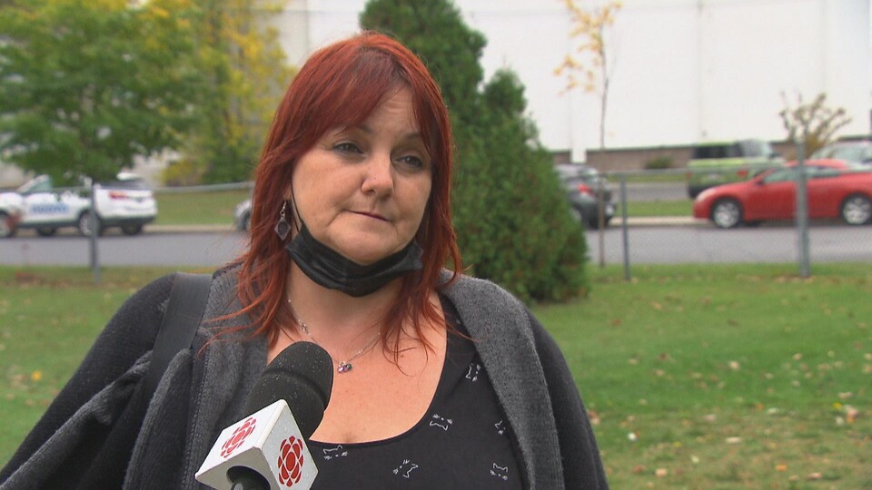 Une femme donne une entrevue devant un parc.