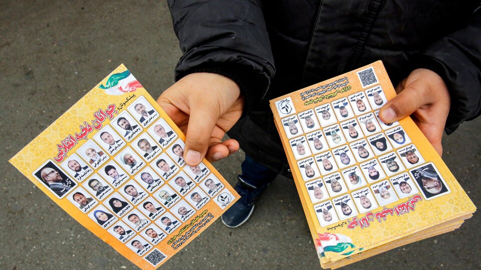 Un homme tend un dépliant avec les photos de 30 candidats.