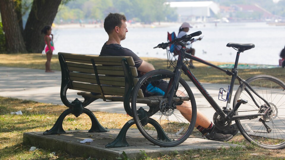 Une personne assise sur un banc avec sa bicyclette.
