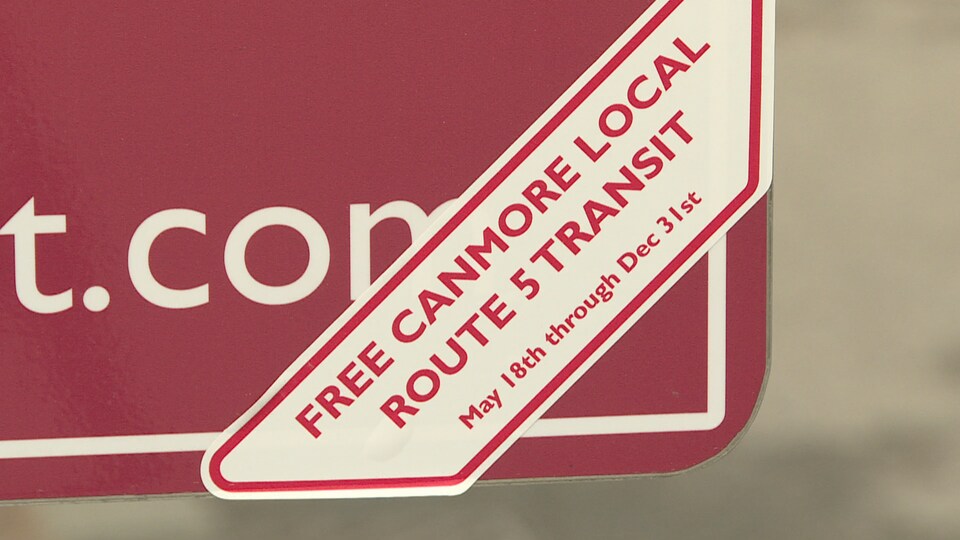 Une petite affiche est collée sur le panneau d'autobus indiquant que le transport en commun est gratuit.