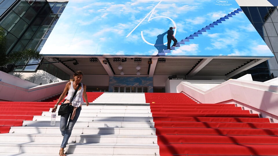 Un escalier couvert de tapis rouge à Cannes. On aperçoit une femme dans le coin gauche de la photo.