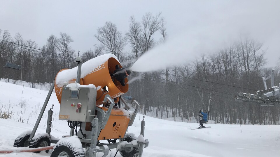 Un canon à neige en action dans une piste de ski.