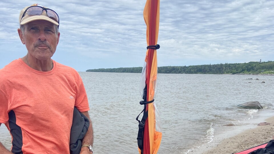Bert ter Hart devant un canot équipé d'un mât sur une plage, en juillet 2022.
