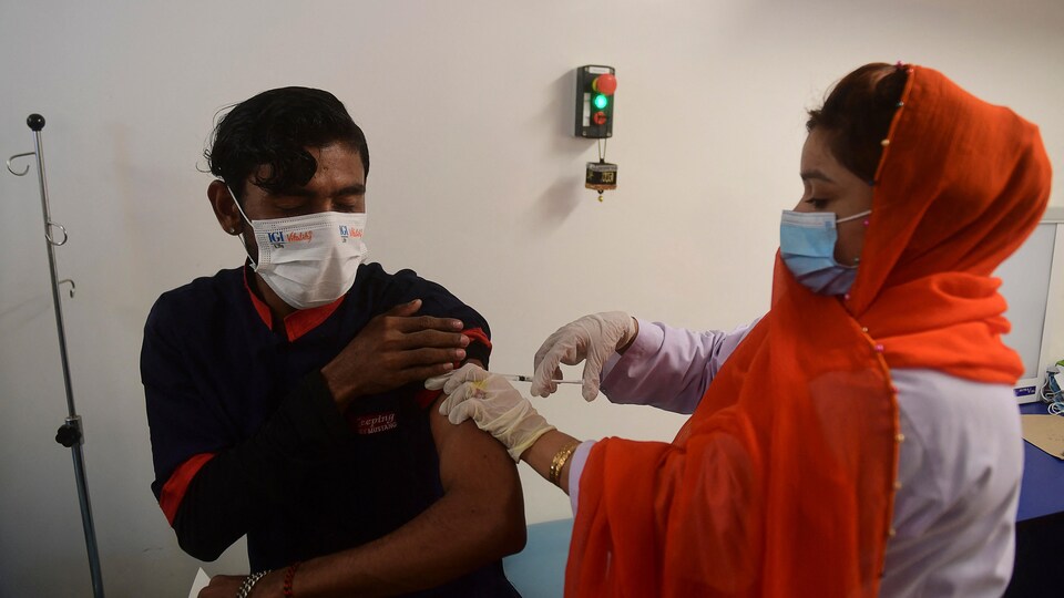 Une femme injecte un vaccin à un homme.