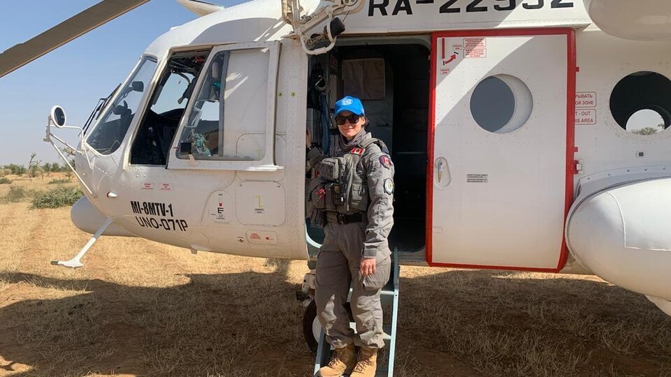 Une militaire est sur les marches d'un hélicoptère