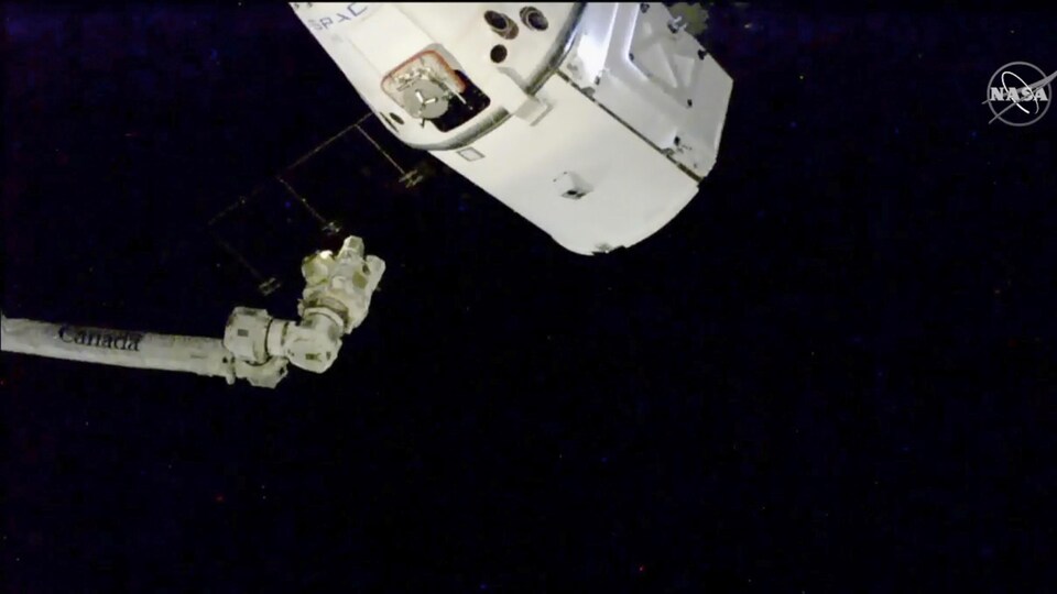 Une capsule spatiale à proximité du bras robotisé de la Station spatiale internationale
