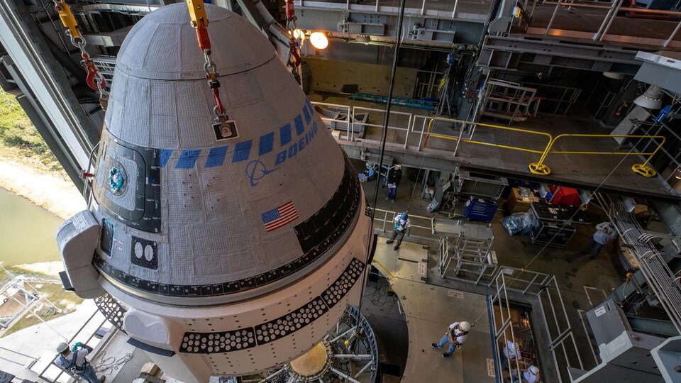 Plan rapproché de la capsule au moment d'être fixée au lanceur.