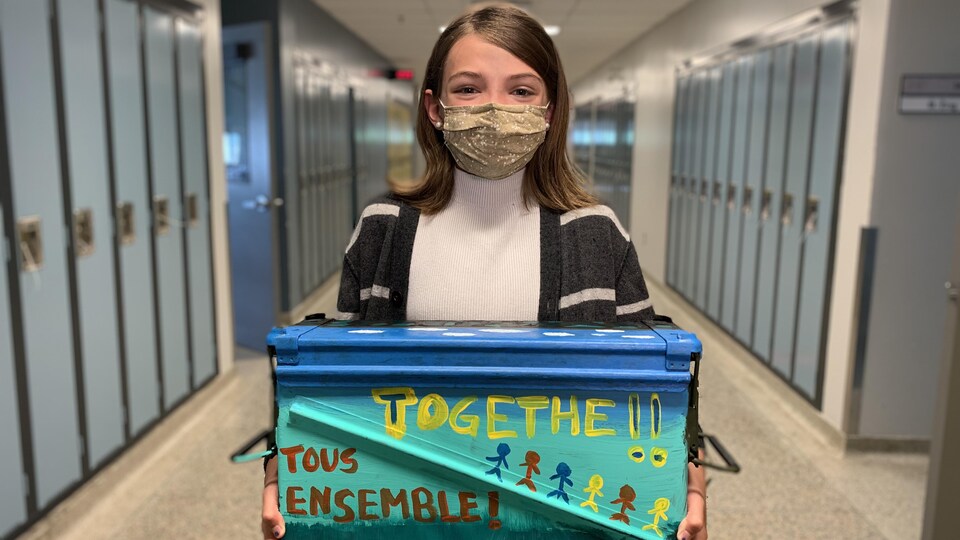 Isabel Feehan tient la capsule temporelle dans ses bras, dans un corridor d'école.