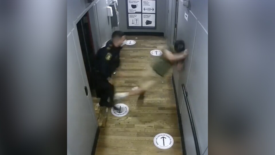 Une capture d'écran de la vidéo montrant un homme être violemment projeté contre un mur par un agent.