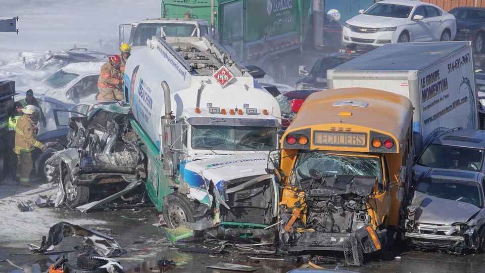 Un camion citerne et un autobus scolaire lourdement endommagés gisent sur la chaussée.