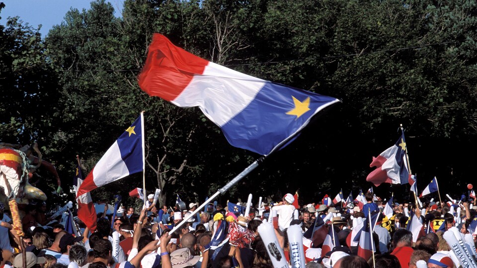 Une foule en liesse brandit des drapeaux acadiens