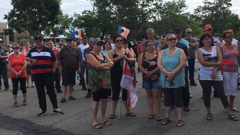 Une foule de manifestants brandissant quelques drapeaux acadiens