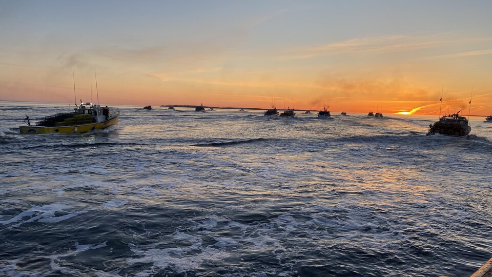 Des bateaux chargés de casiers prennent la mer en direction du soleil levant.