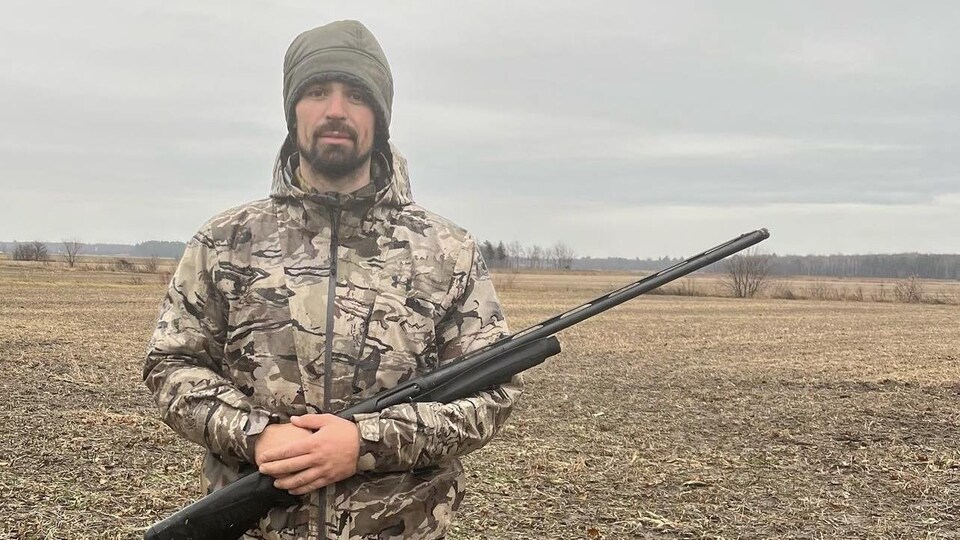 Carey Price tient une arme de chasse dans un champ.