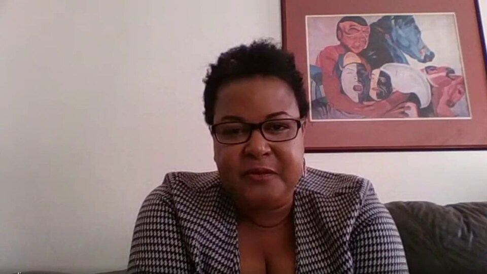 Carline Zamar regardant la camera devant une peinture.