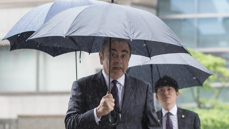 Carlos Ghosn sous un parapluie au centre-ville de Tokyo.
