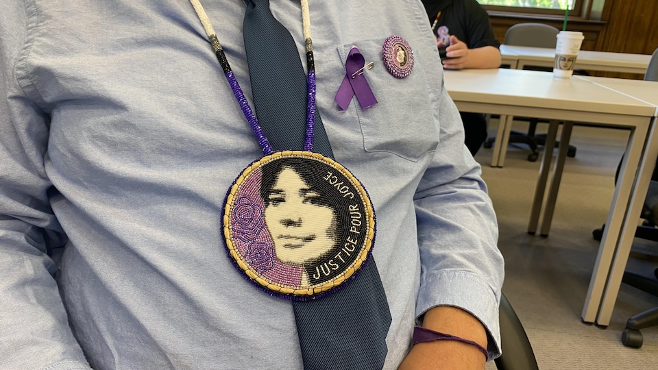 Un homme porte un pendentif fait en perles arborant le visage de Joyce Echaquan et la mention « Justice pour Joyce ».