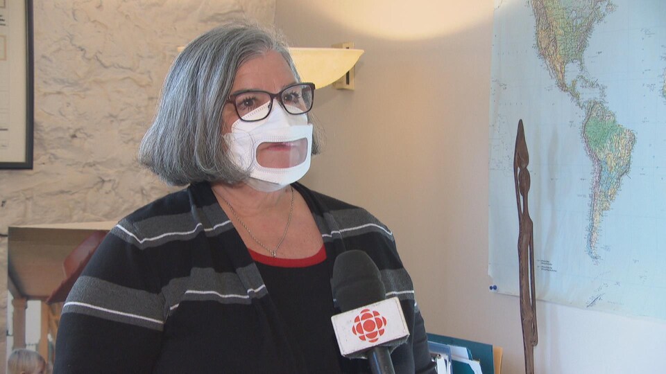 Une femme portant un masque permettant de voir la bouche en entrevue.