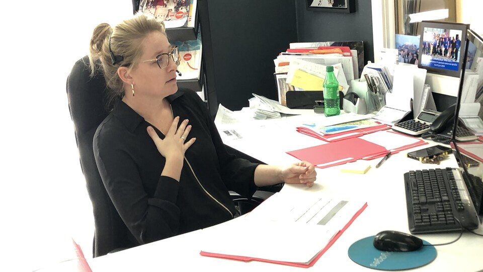 Une femme portant un micro casque parle au téléphone dans son bureau.