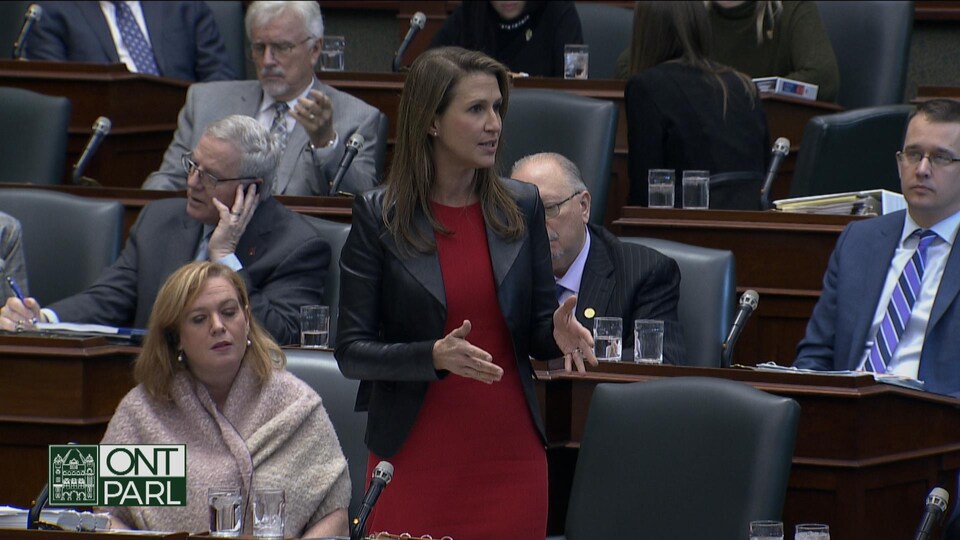 Un femme debout devant un pupitre.