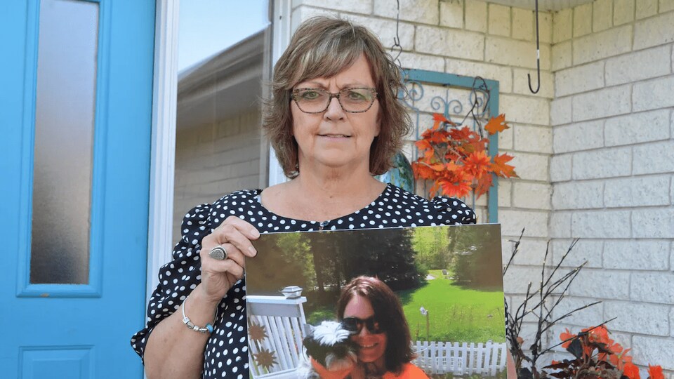 Carolyn Karle tient une photo de sa fille devant son domicile.