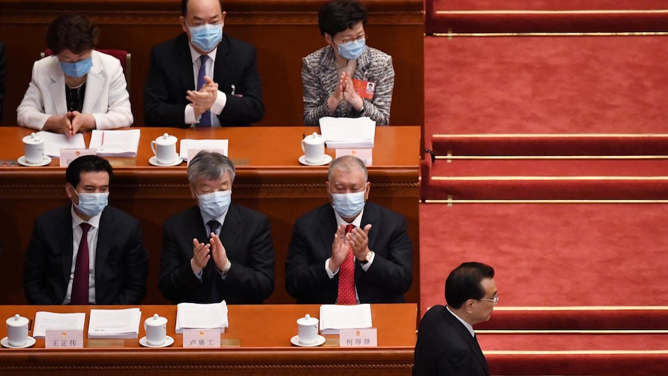 Carrie Lam et d'autres délégués chinois applaudissent le premier ministre chinois Li Keqiang qui retourne s'asseoir.