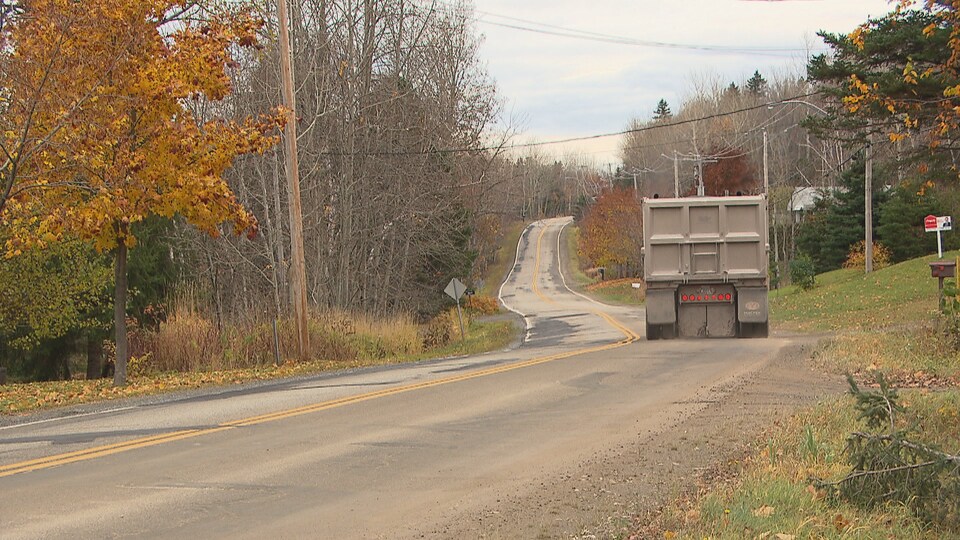 Un camion lourd circule dans un chemin résidentiel.