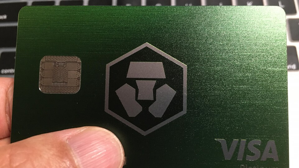Eine Hand, die eine Prepaid-Karte von Crypto.com Visa hält.