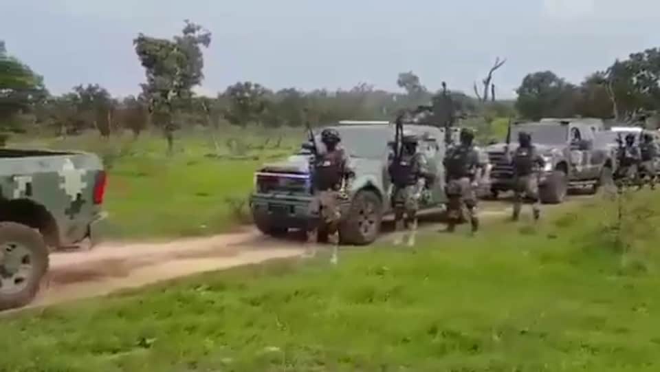 Une dizaine d’hommes armés à côté de camions blindés.