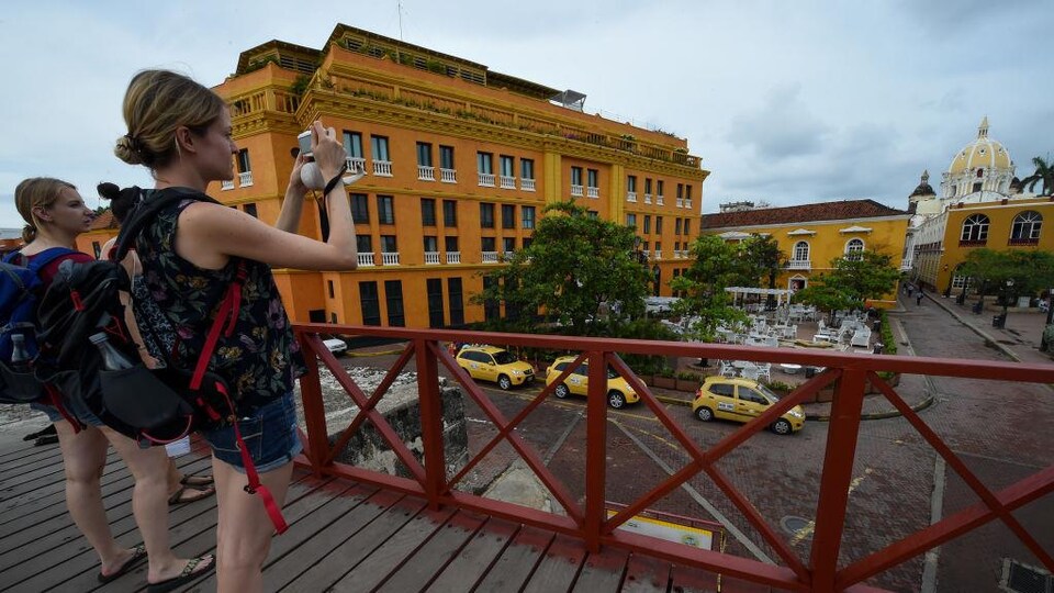 Trois femmes touristes prennent en photo des bâtiments et une église dans la vieille ville de Carthagène, en Colombie. 