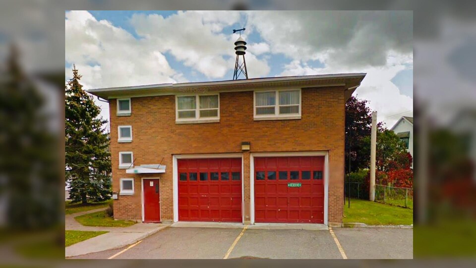 L'ancienne caserne de pompiers de Rimouski. On y voit un garage à porte double rouge et un étage au-dessus, coiffé d'une girouette.