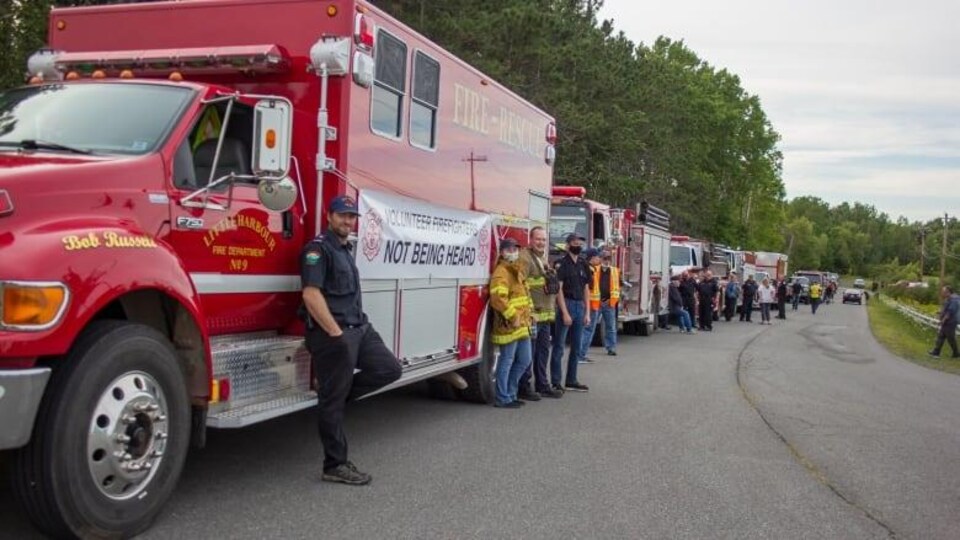 Plusieurs camions et pompiers le long de la route.