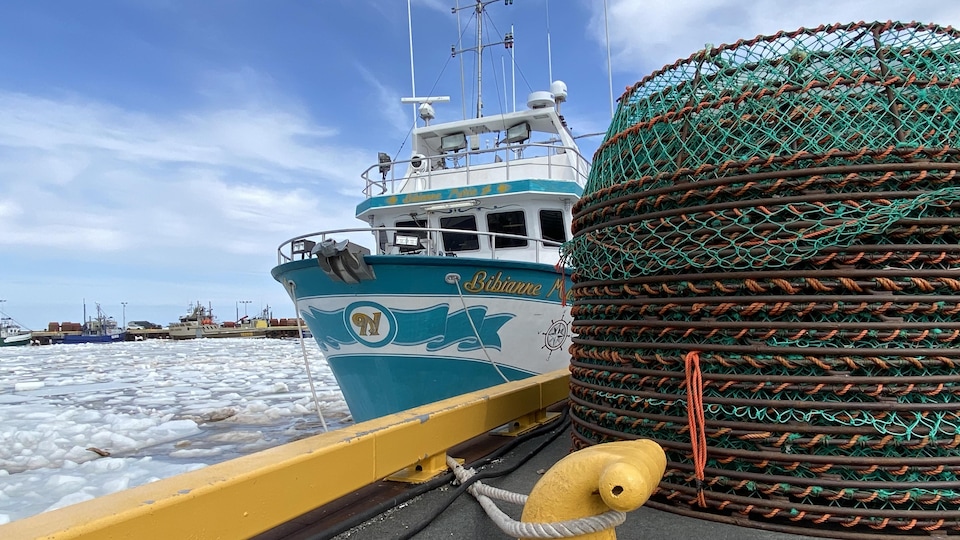 Des casiers à crabes traditionnels sont empilés sur un quai, près d'un bateau.