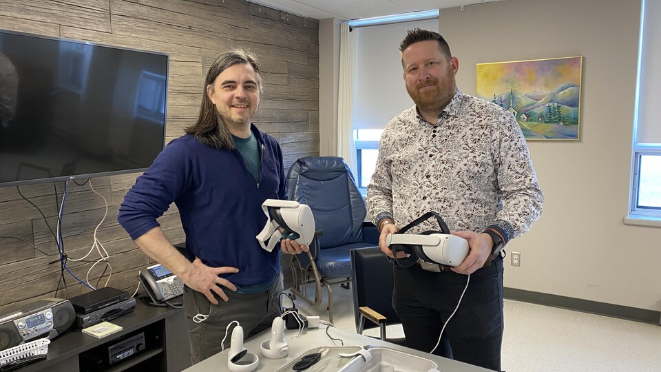 Jean-François Malouin and Louis-Frédéric Lesard hold virtual reality headsets.