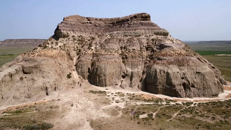Une colline fait de sédiments rocheux au milieu d'un champ des Prairies canadiennes.