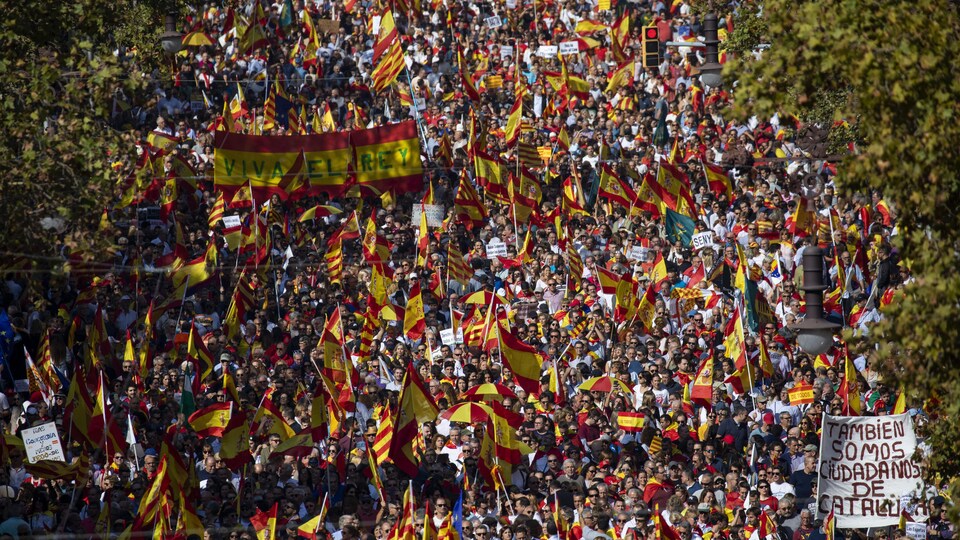 Une foule compacte brandissant des drapeaux aux couleurs de l'Espagne, au soleil.