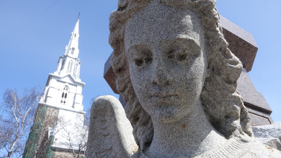 Une statue d'ange au premier plan et le clocher de la cathédrale à gauche.