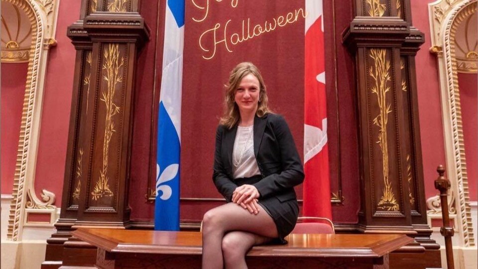 Elle est assise sur un bureau.