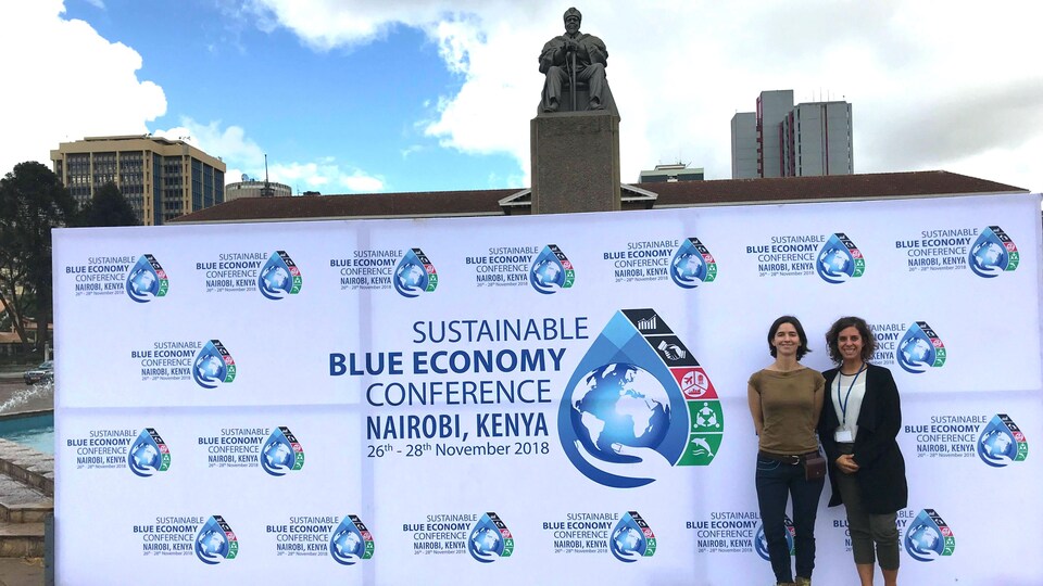 Catherine Lambert-Koizumi et Noémie Giguère devant une banderole de la Conférence sur l'économie bleue durable