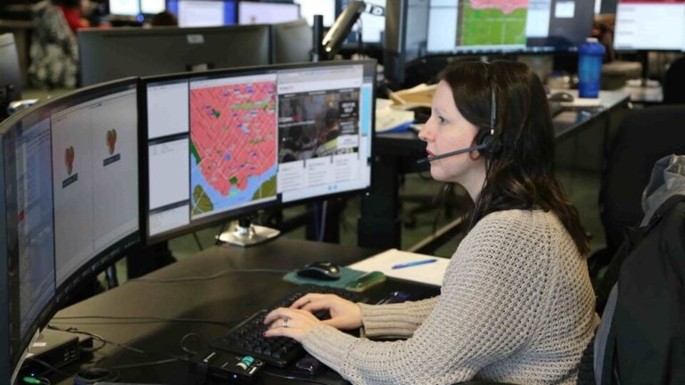 Une préposée au 911 travaille à l'ordinateur.