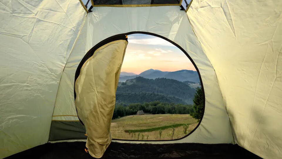Une tente s'ouvre sur des montagnes.