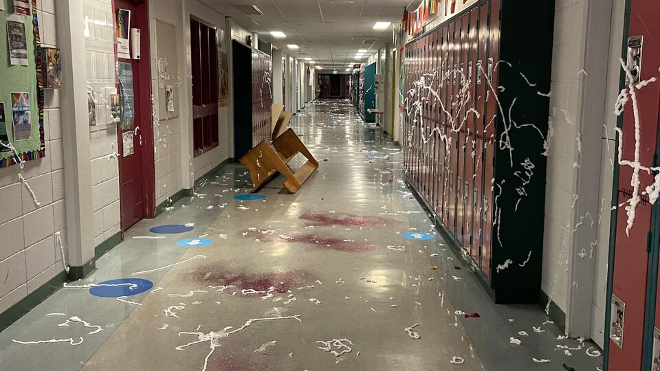 Des oeufs, des retailles de papier, des condiments et du colorant alimentaire répandus sur le plancher et les murs d'un couloir d'école.