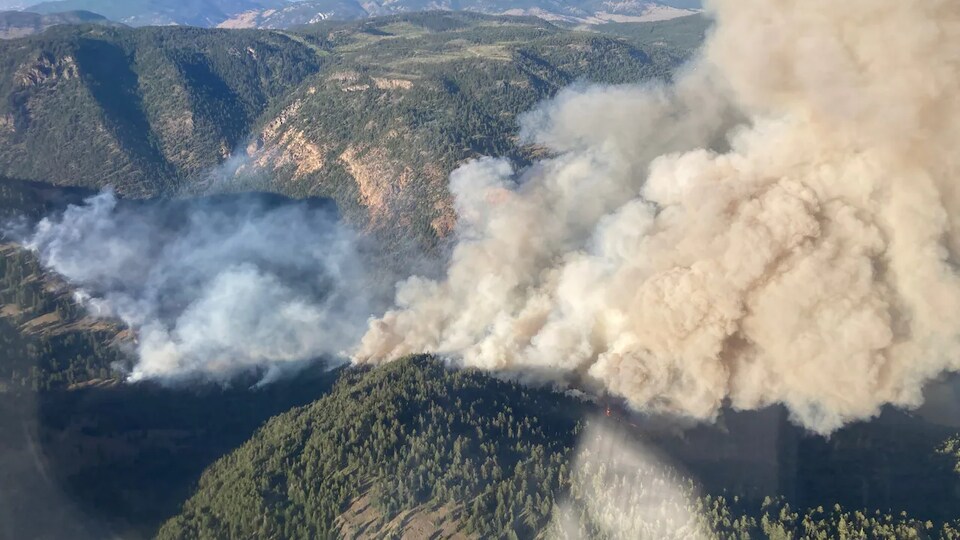Un panache de fumée se dégage d'un incendie dans les montagnes, aux environs de Penticton, en Colombie-Britannique, le vendredi 29 juillet 2022.