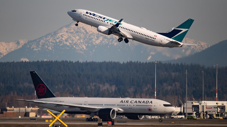Un avion Embraer E195 d'Air Canada se prépare à partir pour Toronto alors qu'un Boeing 737-800 de WestJet décolle à destination de Palm Springs, en Californie, à l'Aéroport international de Vancouver.