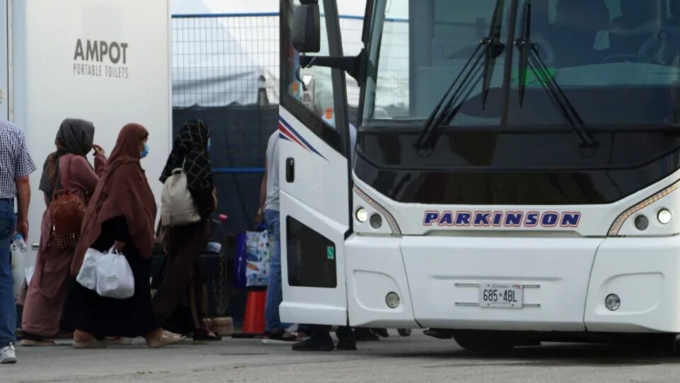 Des réfugiés afghans montent dans un autobus.