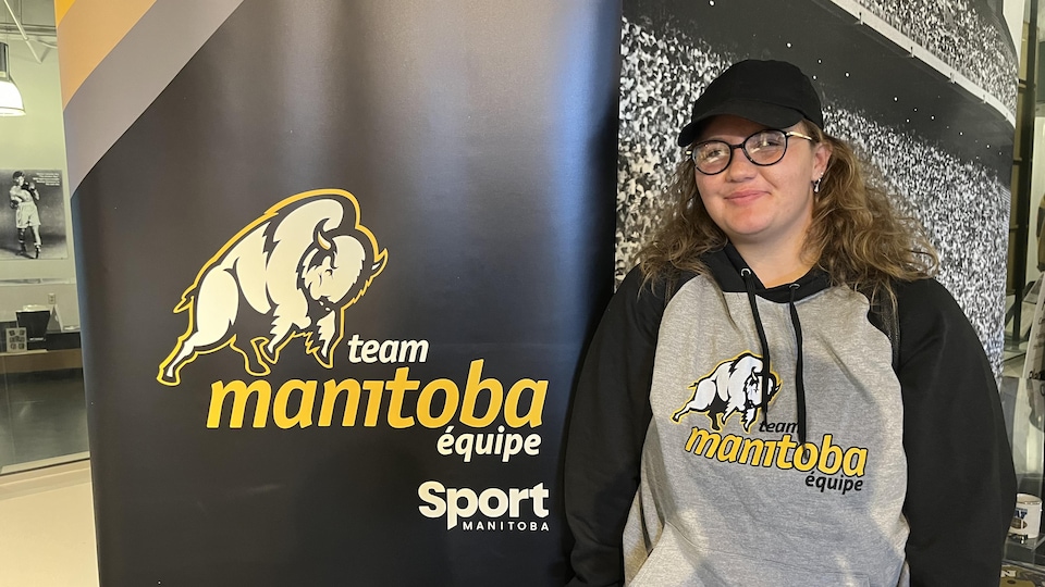Cecilia Swart devant le logo de l'équipe du Manitoba.