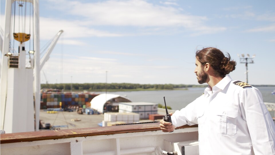 Cédric Goyette sur le bateau qui regarde au loin avec un walkie-talkie dans les mains.