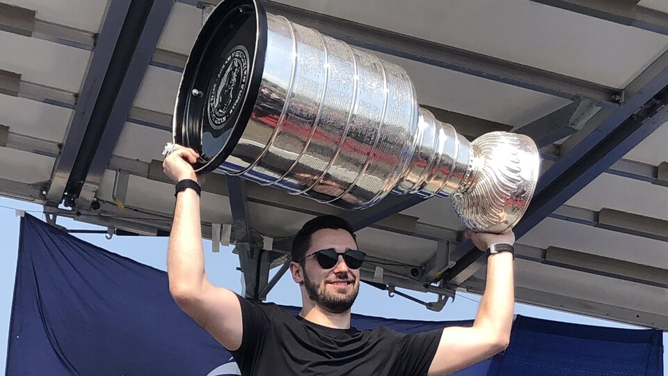 Cédric Paquette tenant la coupe Stanley au bout de ses bras.